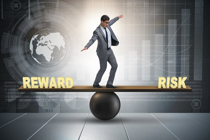 A businessman balancing on a beam between the words Reward and Risk.
