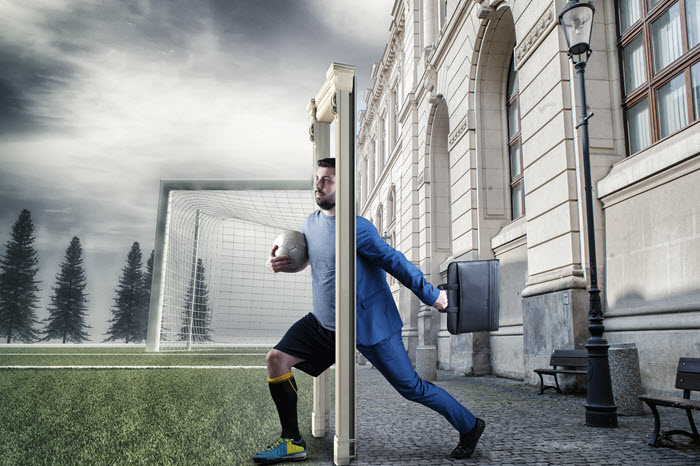A businessman playing goalkeeper in a soccer goal, illustrating teamwork.