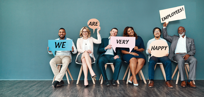 A row of employees holding up signs that read We are very happy.
