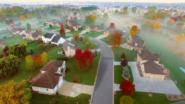 Aerial view of a suburban neighborhood surrounded by autumn trees.