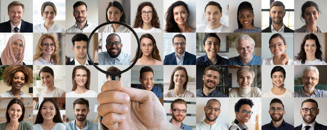 A magnifying glass held over a grid of candidate portraits, singling one out.