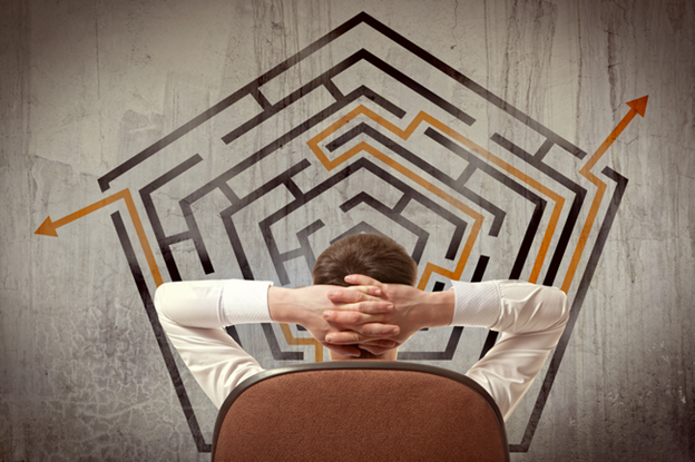 A person leaning back in a chair in front of a maze with an arrow finding the way out.