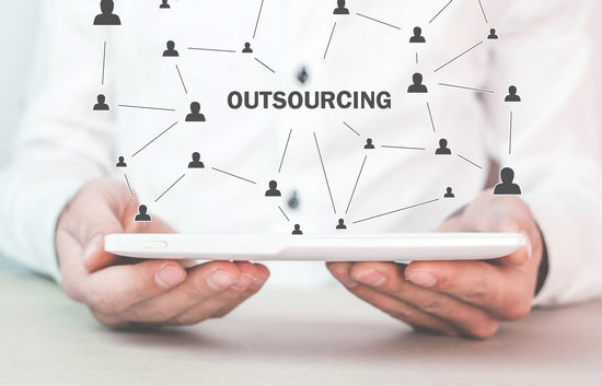 Hands holding a tablet projecting a network of people around the word Outsourcing.