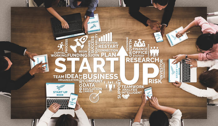 Overhead view of a team working around a table with the word Startup and business icons overlaid.