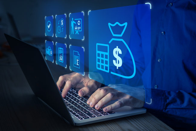 Hands typing on a laptop with glowing money bag and calculator icons above the screen.