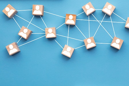 Wooden blocks with person icons connected by lines, representing a network of relationships.