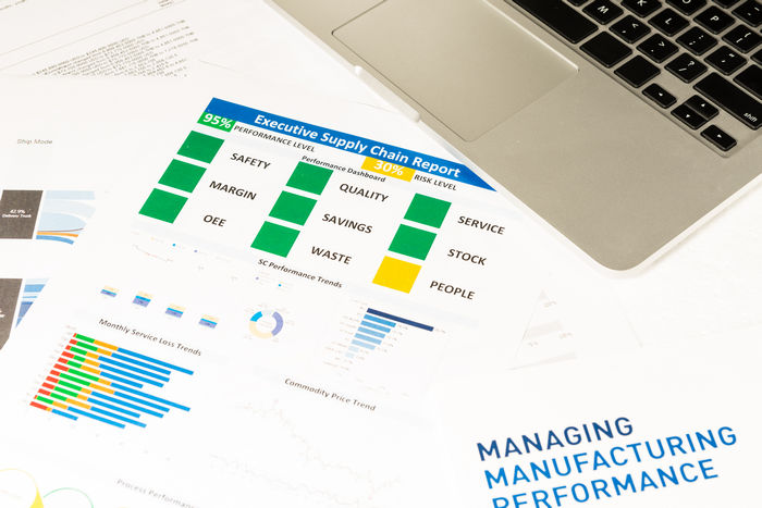 Printed performance dashboards and charts beside a laptop, headed Managing Manufacturing Performance.