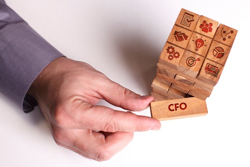 Hands stacking wooden blocks marked with business icons, with the top block labeled CFO.