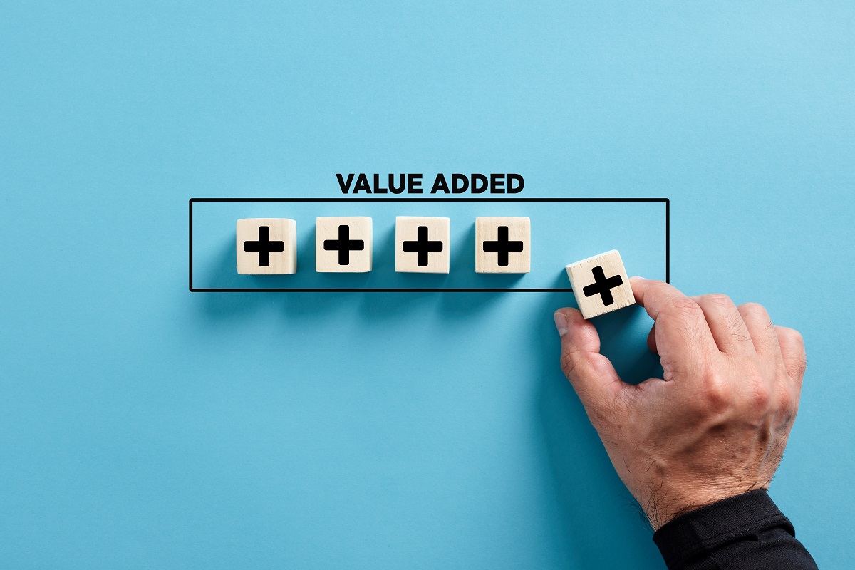 A hand adding a plus sign block to a row beneath the words Value Added.