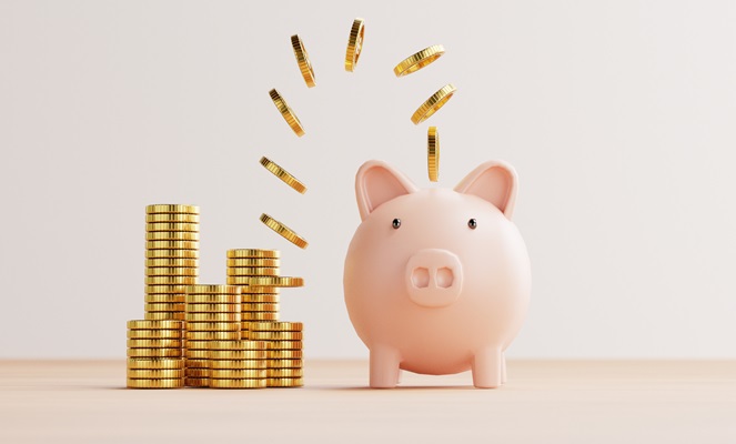 A piggy bank beside stacks of coins with more coins falling toward it.