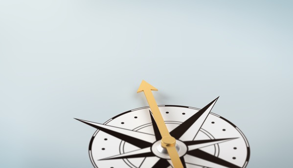 A brass compass resting on a pale blue surface.