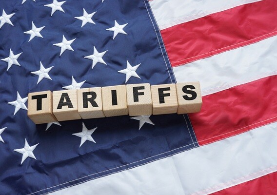 Wooden blocks spelling Tariffs resting on an American flag.