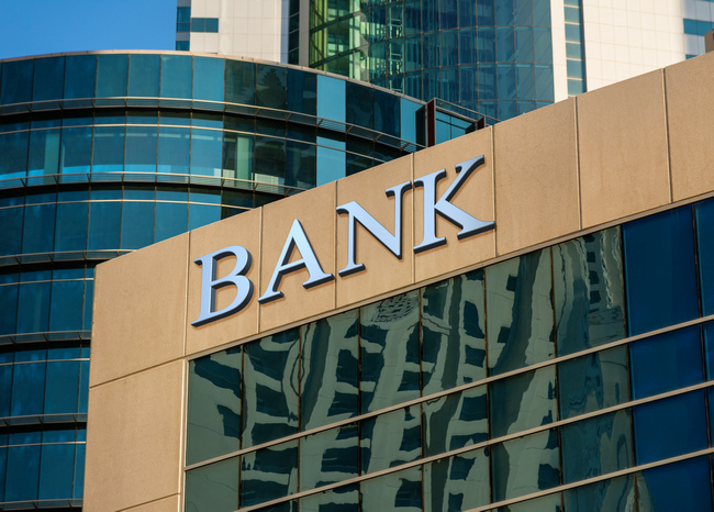 The word Bank carved into the facade of a modern glass office building.