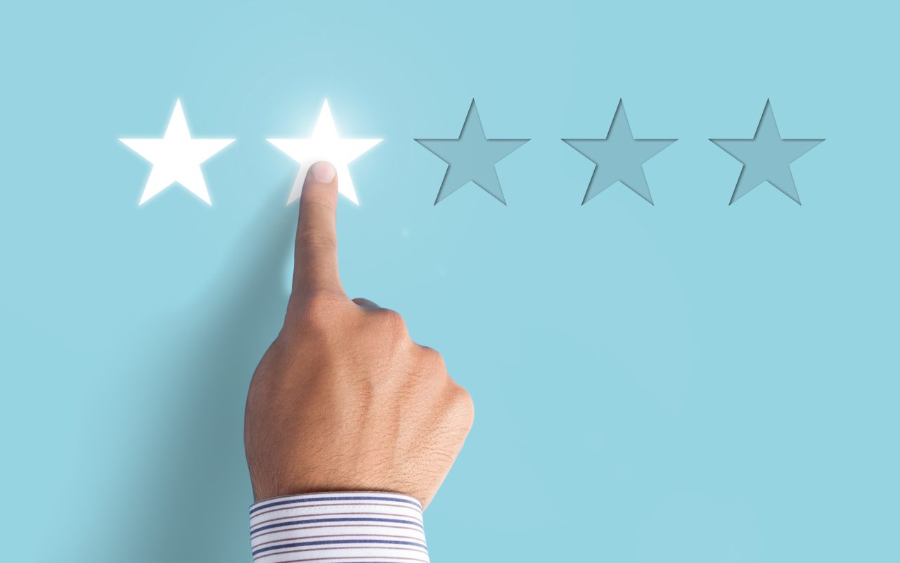 A hand pointing at the second of five stars in a rating.