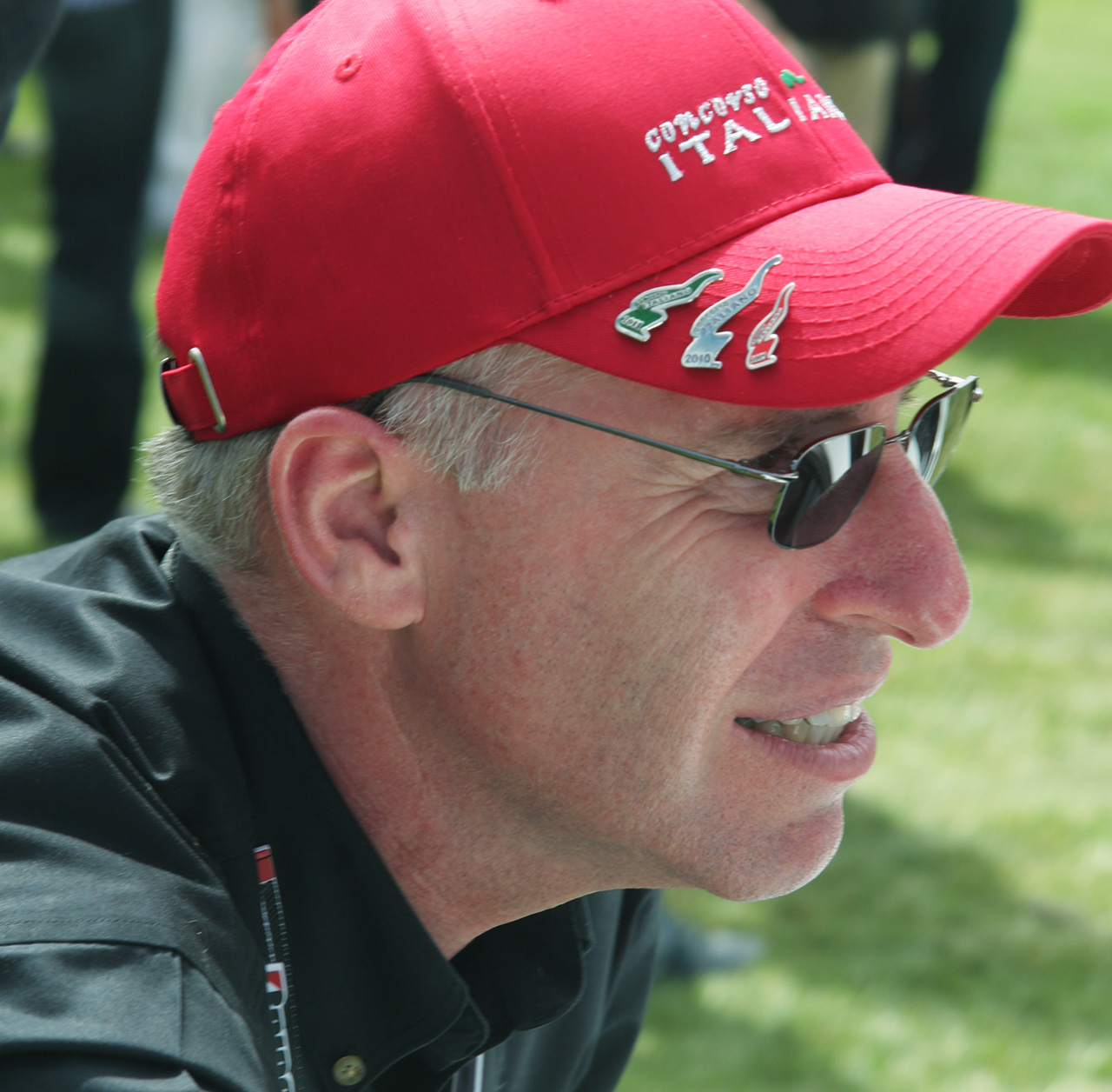 Close-up of Tom McDowell in sunglasses and a red Concorso Italiano cap.
