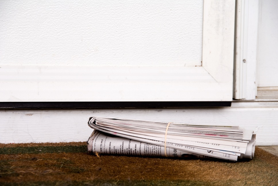 A rolled newspaper lying on a doorstep.