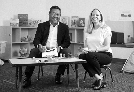 Becky Todd of CFO Selections and Gary Yamamoto talking at a classroom table at Kindering.