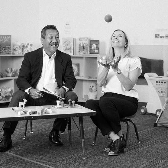 Becky Todd of CFO Selections and Gary Yamamoto seated at a child-sized table in a Kindering classroom.