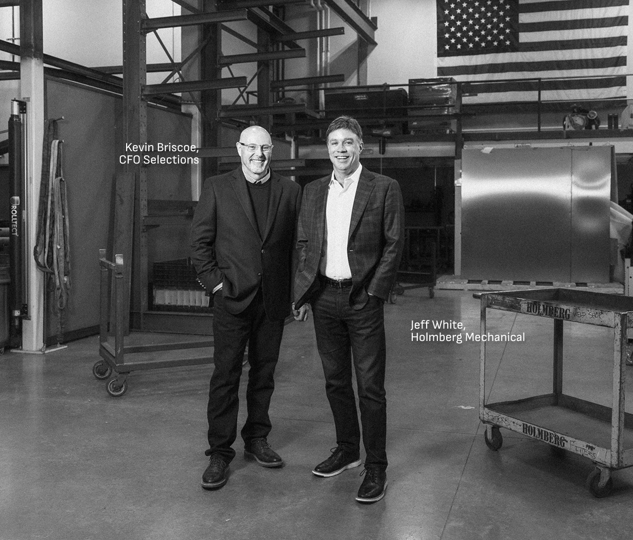 Kevin Briscoe of CFO Selections and Jeff White of Holmberg Mechanical in the shop beneath an American flag.