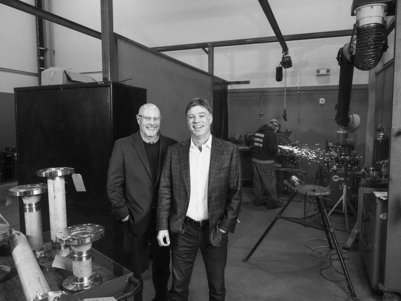 Kevin Briscoe and Holmberg Mechanical owner Jeff White beside fabrication equipment