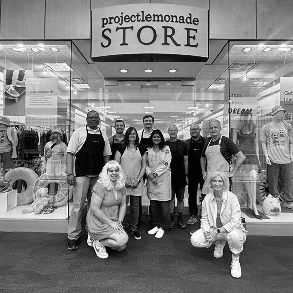 A group of volunteers posed together in front of the Project Lemonade Store.