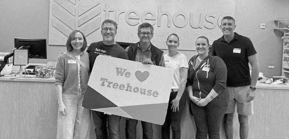 A group of people holding a "We love Treehouse" sign at the Treehouse offices.